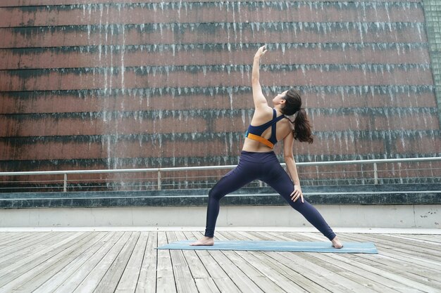 Young attractive woman doing stretching yoga exercise in the park