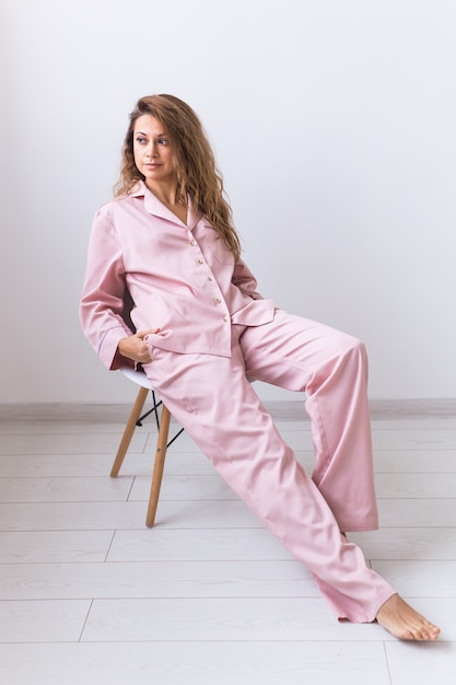 Молодая привлекательная женщина, одетая в красивую красочную пижаму, изображающая модель в своей гостиной