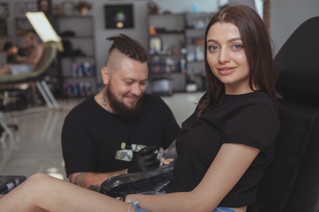 Young attractive woman getting new tattoo by professional tattooist