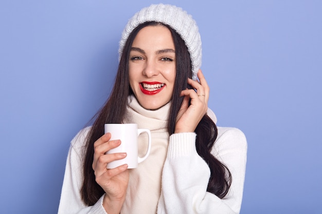 Young attractive woman holding cap of hot beverage in her hands