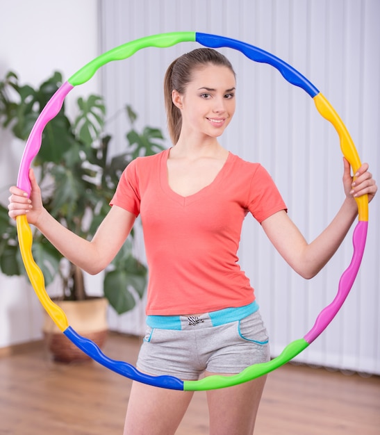 Photo young attractive woman holding hula hoop.