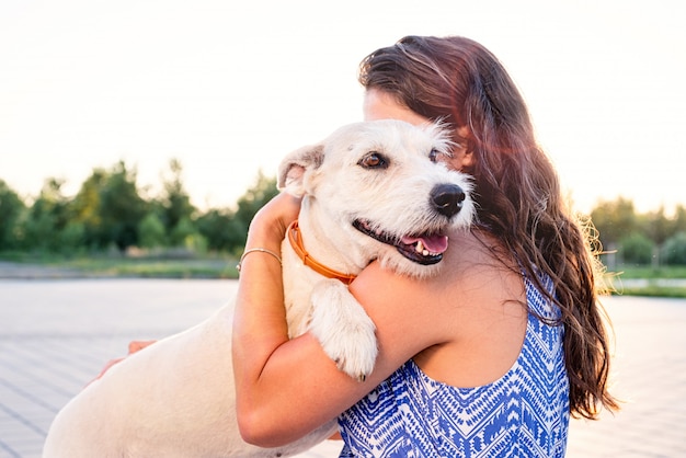 Foto giovane donna attraente che abbraccia il suo cane nel parco