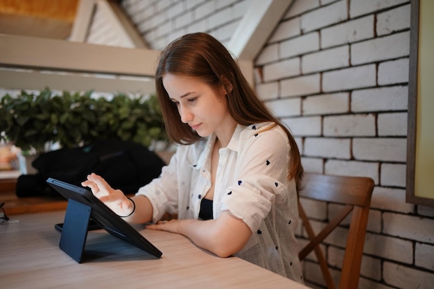 カフェでモバイル タブレットと対話する若い魅力的な女性