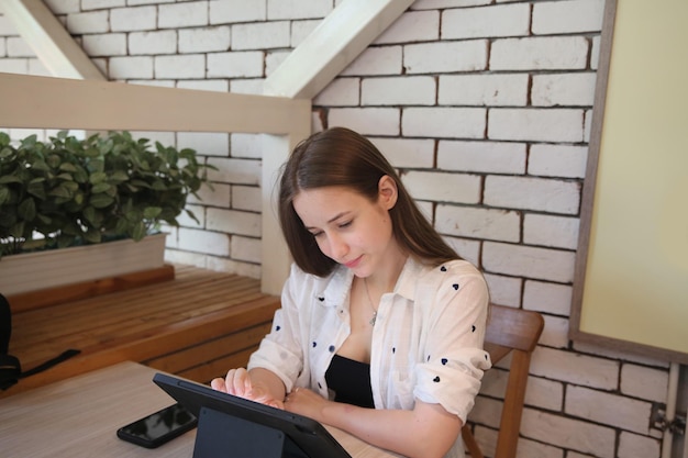 Young attractive woman interacting with the mobile tablet in\
cafe