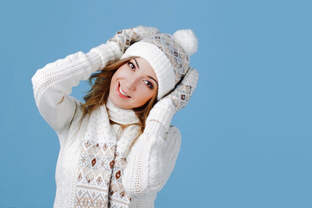 Молодая и привлекательная женщина в вязаном свитере, шарфе, шапке, синего цвета