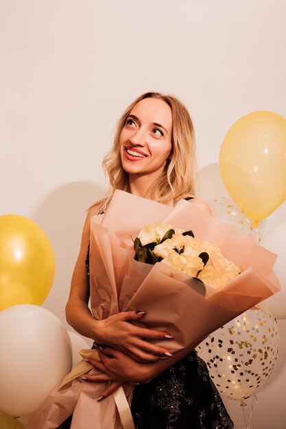 Foto giovane donna attraente con un vestito lungo con rose e palloncini festa di celebrazione