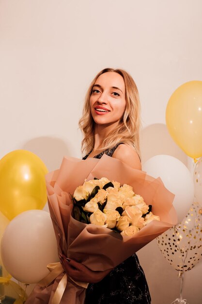 Young attractive woman in long dress with roses and balloons Party celebration