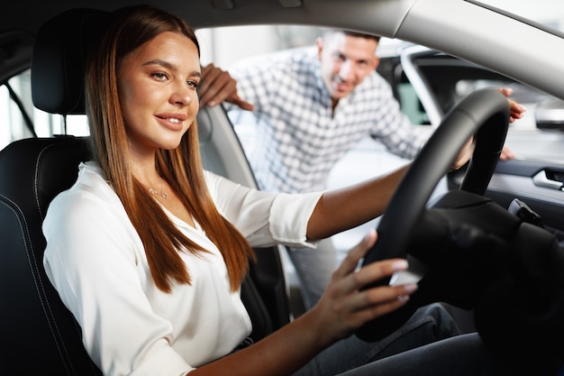 Foto giovane donna attraente alla ricerca di una nuova auto in uno showroom