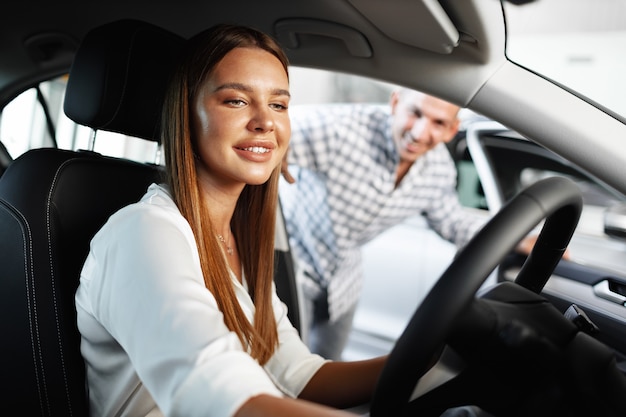 Young attractive woman looking for a new car in a showroom