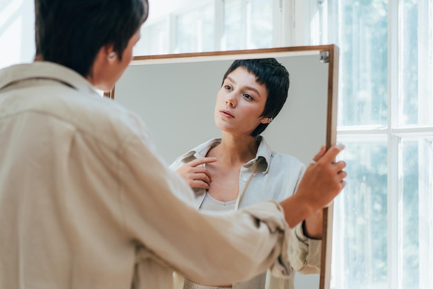 a young attractive woman looks at her reflection in the mirror