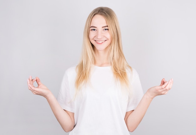 Young attractive woman meditates in the lotus position over white