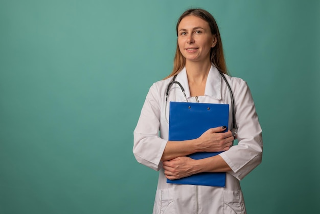 Young attractive woman nurse or doctor in a white coat with file on background