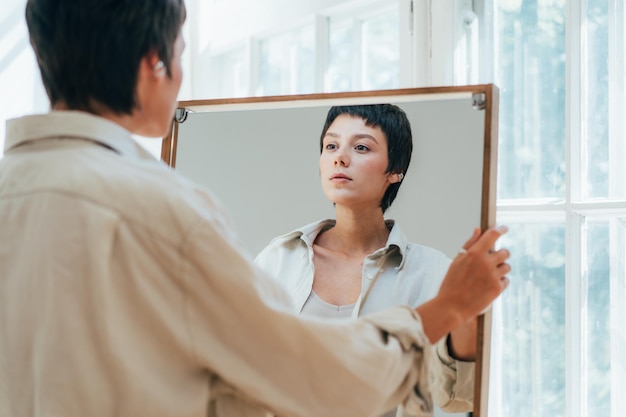 a young attractive woman peers at her reflection in the mirror