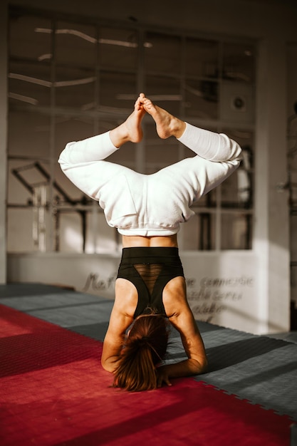 Young attractive woman practicing yoga headstand garuda salamba sirsasana working out by pool above