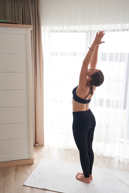 Young attractive woman practicing yoga at home standing in tadasana exercise mountain pose working