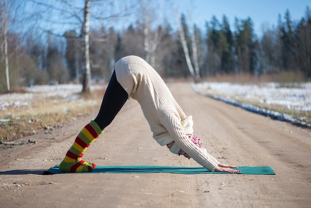 Foto giovane donna attraente che pratica yoga all'aperto yoga invernale