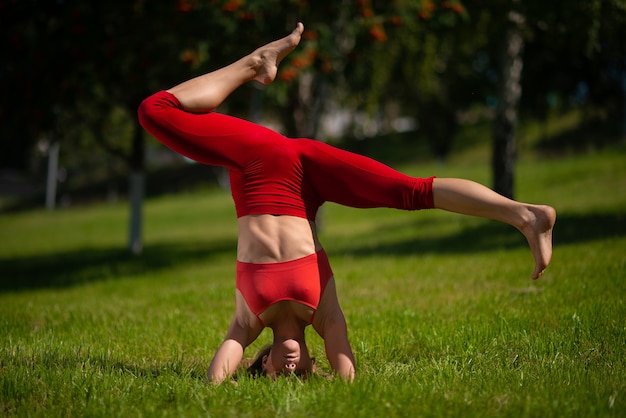 Young attractive woman practicing yoga outdoors. The girl performs a handstand upside down