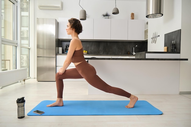 Young attractive woman practicing yoga and stretching body at home girl standing in asana wearing ac
