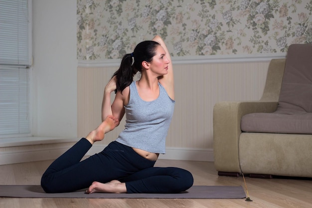 Young attractive woman practicing yoga wearing sportswear meditation session home interior