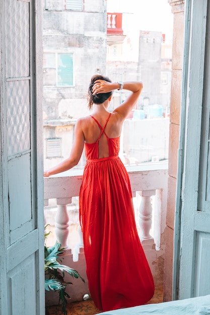 Young attractive woman in red dress on old balcony in apartment in Havana