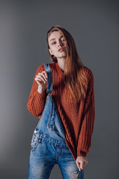 灰色の背景に赤いセーターを着た若い魅力的な女性感情