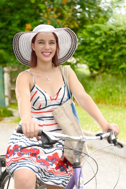 Foto giovane donna attraente che guida una bicicletta