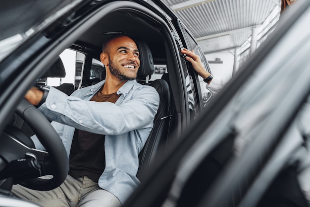 Photo young attractive woman salesperson in car showroom showing a car to her male client