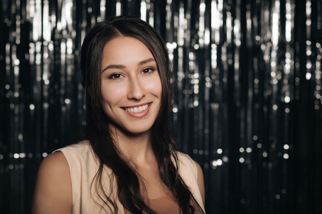 Photo a young attractive woman smiles at a party on a silver shiny background