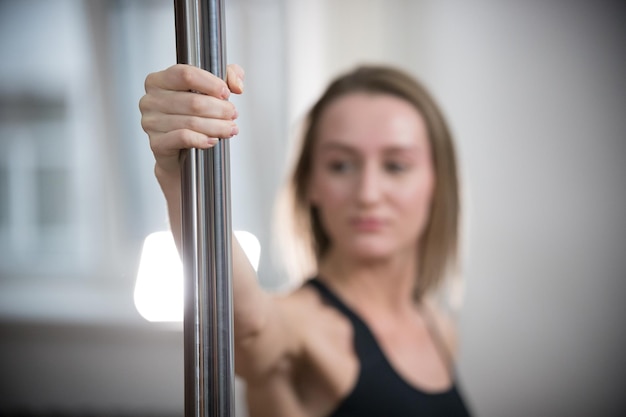 Young attractive woman in sport bra holding a pole Pole close up