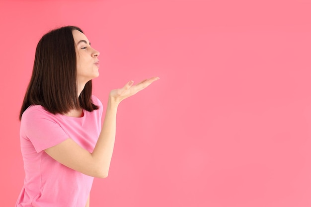 Young attractive woman in t-shirt on pink background