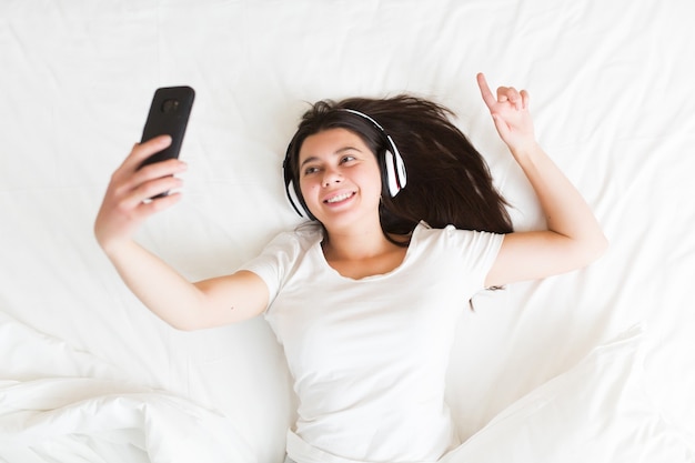 Young attractive woman taking selfie at home on the bed