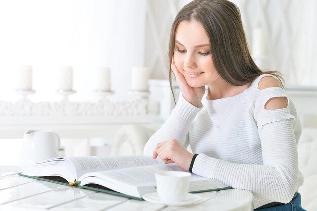 Young attractive woman with book and cup of coffee