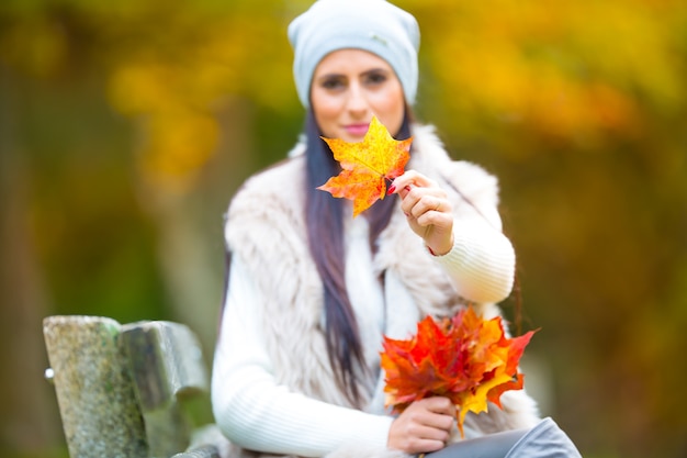 手に花束の紅葉を持つ若い魅力的な女性。秋。