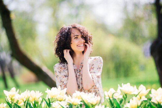 Young attractive woman with curly long hair posing in spring blooming garden, apple trees