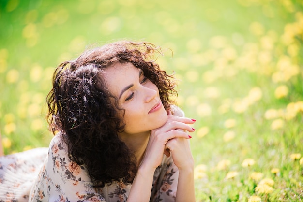 Giovane donna attraente con capelli lunghi ricci in posa nel giardino fiorito primaverile, alberi di mele