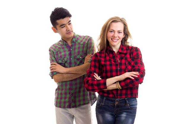Young attractive woman with long chestnut hair and young handsome man with dark hair in plaid shirts and jeans on white background in studio