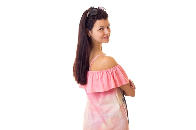 Young attractive woman with long dark hair in pink dress with palm trees and black sunglasses on white background in studio