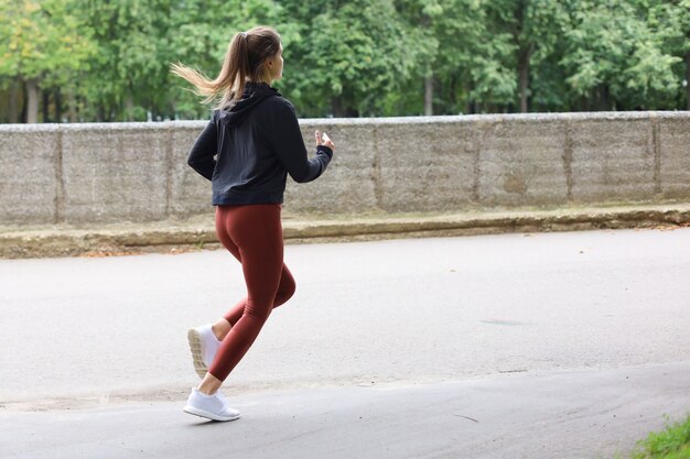 Giovane donna attraente con un perfetto corpo snello che corre all'aperto. fitness e concetto di corsa.