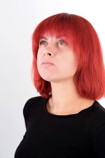 A young attractive woman with a short orange hairstyle in a black Tshirt and jeans posing in the studio on a white background