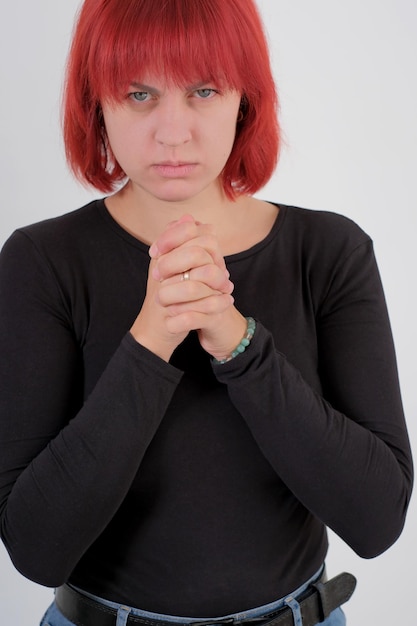 A young attractive woman with a short orange hairstyle in a black Tshirt and jeans posing in the studio on a white background