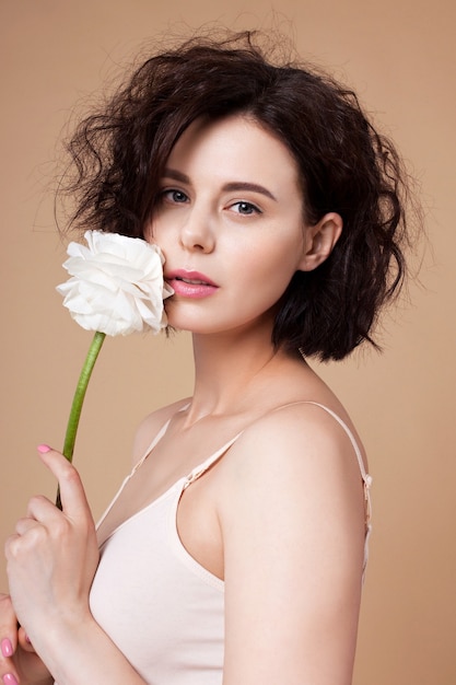 Young attractive woman with white flower near face