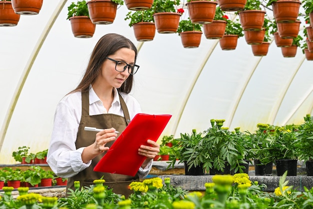 Foto giovane donna attraente che lavora al vivaio di piante fiori in crescita