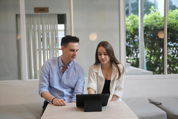 Young attractive woman and young man are interacting with the mobile tablet in cafe