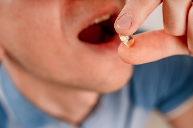 A young aucasian man takes a pill Man making medicine at home closeup