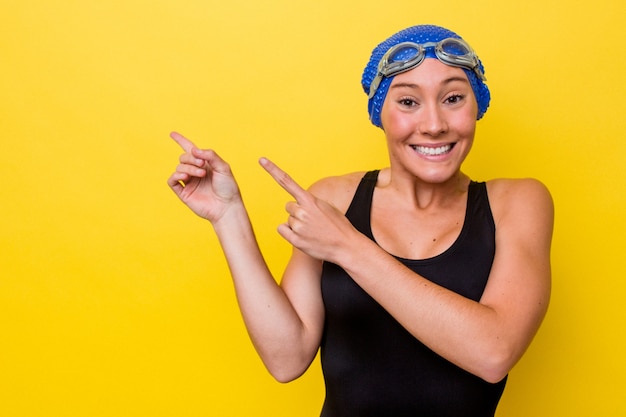 Photo young australian swimmer woman isolated on yellow background shocked pointing with index fingers to a copy space.