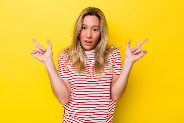 Young australian woman isolated pointing to different copy spaces, choosing one of them, showing with finger.