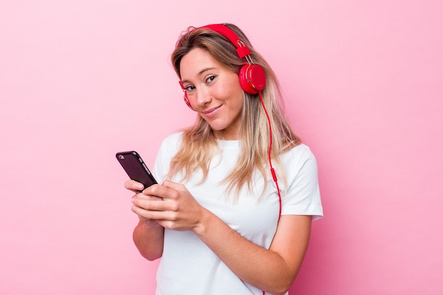 Giovane donna australiana che ascolta la musica isolata su fondo rosa