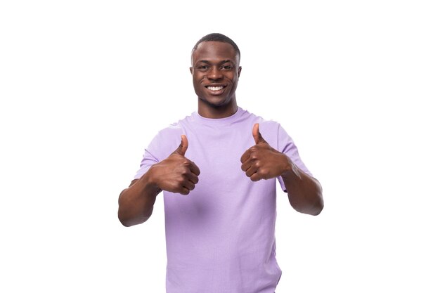 A young authentic american guy dressed in a light lilac tshirt is confident in himself on a white