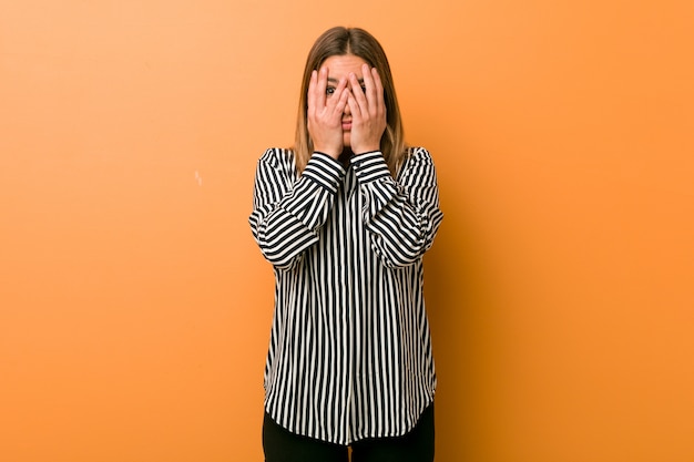 Photo young authentic charismatic real people woman against a wall blink through fingers frightened and nervous.