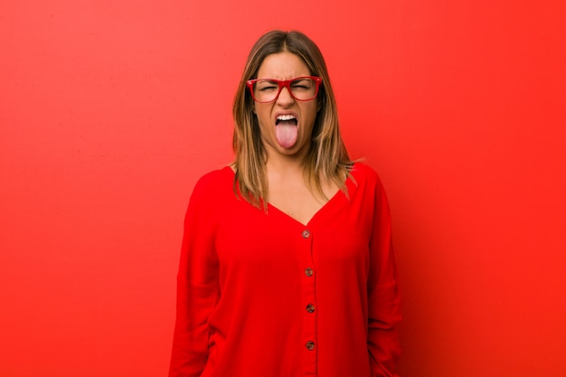 Young authentic charismatic real people woman against a wall funny and friendly sticking out tongue.